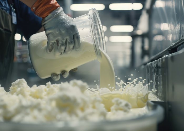 trabajador-vertiendo-leche-en-un-recipiente-para-la-transformacion